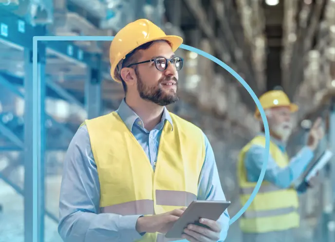 A man in a hard hat and safety vest holding a tablet with the outline of the letter